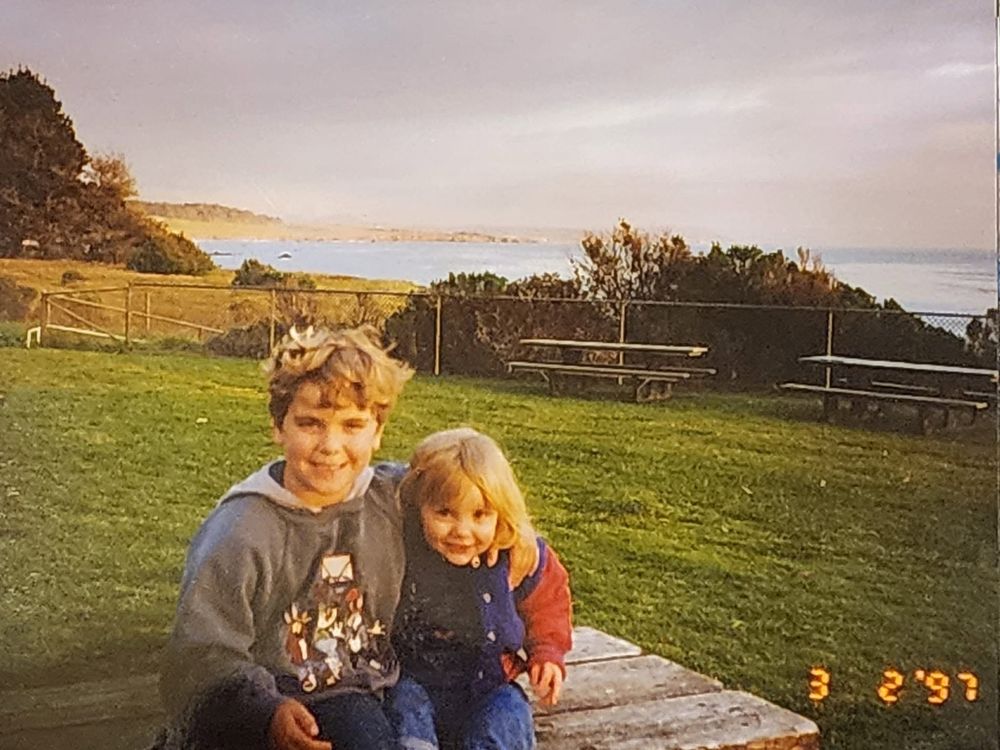 Two kids sitting on the grass at golden hour